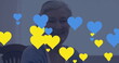 Image of blue and yellow hearts over senior caucasian woman using tablet
