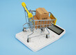 Shopping trolley on carton boxes on white calculator on blue background. Smart purchasing  concept.	