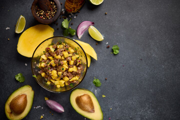 Cooking traditional tuna and mango tartare - chopped and mixed tuna, mango, cilantro and onion in a glass bowl