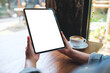 © Farknot Architect - Mockup image of a woman holding digital tablet with blank white desktop screen in cafe