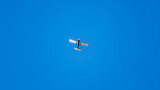 Fototapeta Nowy Jork - Small ultralight airplane with overhead wing and single propeller flying in sunset sky.