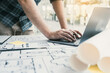 © wutzkoh - Architect working new project and using laptop with in office.