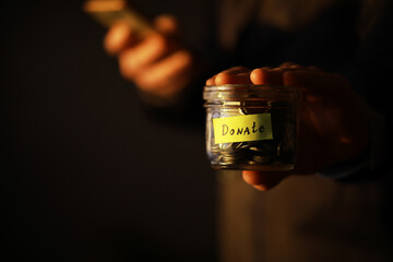 Sticker - Businessman hand putting money (coin) in the glass jar, vintage tone effect