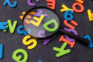 Wall Mural - Magnifying glass with many wood letters of English alphabets, learning English concept