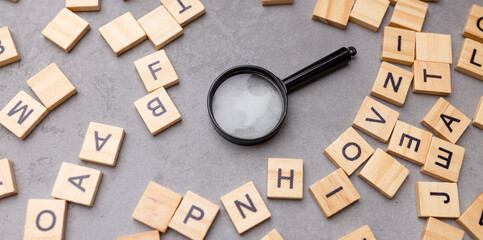 Wall Mural - Magnifying glass with many wood letters of English alphabets, learning English concept