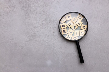 Wall Mural - Magnifying glass with many wood letters of English alphabets, learning English concept