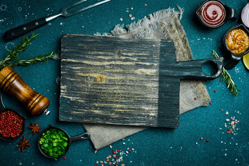 Wall Mural - Kitchen cutting board on table with spices, vegetables and herbs. Free space for a recipe. Rustic style. On a dark background.