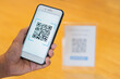 Scanning QR code with mobile smart phone over wooden table background. Qr code payment, E wallet.