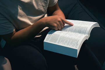 Spirituality and religion concept. Reading a book. Christian man's hands while reading the Bible outside.Sunday readings, Bible education.