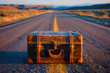 Vintage suitcase on empty road, adventure and travel concept.