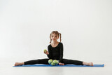 Fototapeta Na ścianę - Healthy eating, green apples. Little girl in yoga clothes is on the fitness mat