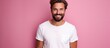 © vxnaghiyev - A delighted smiling brunette man with a beard wearing a white T shirt poses in a fashion portrait against a pink background leaving room for additional images