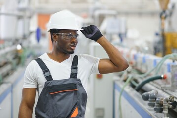 Portrait of African American male engineer in uniform and standing in industrial factory