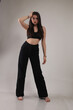 © Velychko - Portrait of a beautiful fashion model in the studio on a light background, wearing a black short clothes and trousers, barefoot