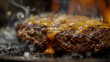 A delicious juicy beef patty sizzling on the grill