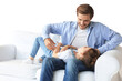 © ty - Smiling young father lying on couch at living room and play with happy little daughter on a transparent background
