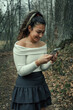 A teenage girl takes pictures in a spring forest on a smartphone.