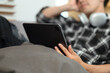 Carefree young man lying on couch and watching movie on digital tablet at home
