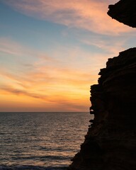 Wall Mural - an ocean sunset at an outcropping island with rocks on it