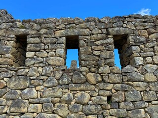 High-angle shot of ancient wall of ruins in Machu Picchu surrounded by a clear blue sky