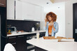 © SHOTPRIME STUDIO - Woman holding pizza box in front of kitchen counter, preparing to enjoy a delicious meal at home