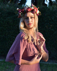 Poster - close up portrait of pretty blonde female model wearing a flower crown wreath and purple dress.  green nature  plants and trees in background