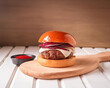 Freshly cooked burger on wooden board on a light background