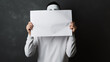 a man with a white sheet of paper covers his face with it, hides himself. announcement blank