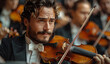 © Natalia - A professional musical ensemble playing in an old concert hall. A man with curly hair and beard plays the violin at the front of the stage, a symphonic orchestra is behind him.