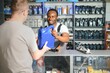 © Serhii - car mechanic in a workshop at his workplace, young male in uniform stands posing at camera