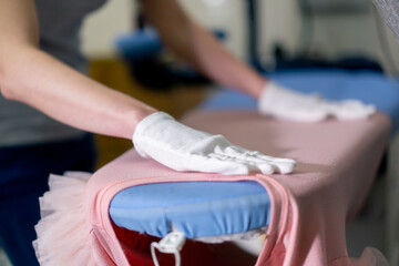 close-up professional dry cleaning young girl lays out pink jacket for ironing professional equipment