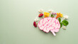 Flat layout of human brain anatomy with colorful fresh flower on green background. Mental health care, positive thinking and creative idea concept.