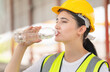 Caucasian female engineer drinking water at the precast factory site, Young forman worker drinking water at construction site.
