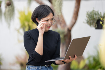 A woman wearing glasses is looking at a laptop