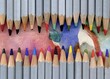 Set wooden colored pencils on artwork background. Colored pencils laying in row. 