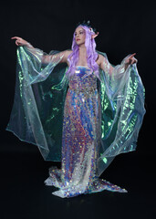 Sticker - Full length portrait of beautiful female model with long purple hair wearing elf ears, a fantasy fairy crown and  rainbow glitter sequin ball gown. graceful standing pose,  isolated in dark studio bac