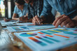 © PHAISITSAWAN - Hands business team having a meeting to analyze data graph charts for a marketing plan.