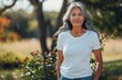 © Umme - Middle aged Senior woman wearing blank white t-shirt, standing outdoors, Old Mature confident lady, mockup, copy space
