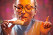 An adult woman in glasses enjoys eating pizza