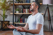 © InsideCreativeHouse - Middle aged sporty man meditating alone at his living room floor sitting. Peaceful calm hipster fit guy practicing yoga in lotus pose indoors holding hands in mudra. Freedom and calmness concept.
