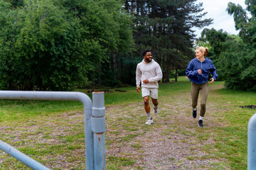 Wall Mural - Friends jogging through a park, smiling and enjoying their run. They are dressed in sportswear, highlighting an active and healthy lifestyle.