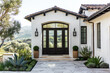 © Joseph Hendrickson - A front door detail of a spanish style home with a black front door surrounded by windows, black light fixtures, and a view of the valley behind it.