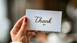 © Bnz - Hand holding a thank you card on a blurred background, Concept of gratitude expression, personal acknowledgment, appreciation and personal touch