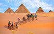 A Group of tourist riding a camel - Camels in Giza Pyramid Complex - Cairo, Egypt