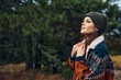 © SHOTPRIME STUDIO - A young woman in a cozy sweater and beanie standing amidst the serene beauty of a forest getaway