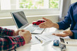 © ArLawKa - A close-up image of a salesperson introducing a customer sitting at a table with a small car and car keys. car dealer sales And the new owner has entered into a contract to sell and lease cars.