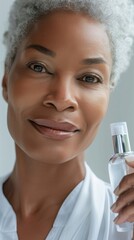 Wall Mural - A close-up of a smiling woman with gray hair holding a clear bottle of liquid possibly a skincare product.