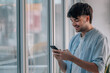 © carballo - young man with mobile phone indoors next to the window