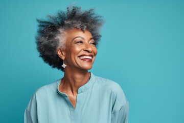 Sticker - Portrait of a joyful afro-american woman in her 60s smiling at the camera isolated in pastel teal background