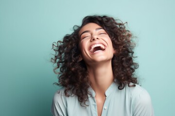 Wall Mural - Portrait of a content woman in her 30s laughing in pastel gray background